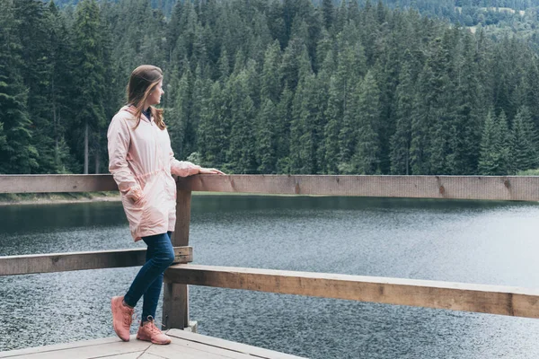 Жінка стоїть в пірсі біля гірського озера і лісу — стокове фото