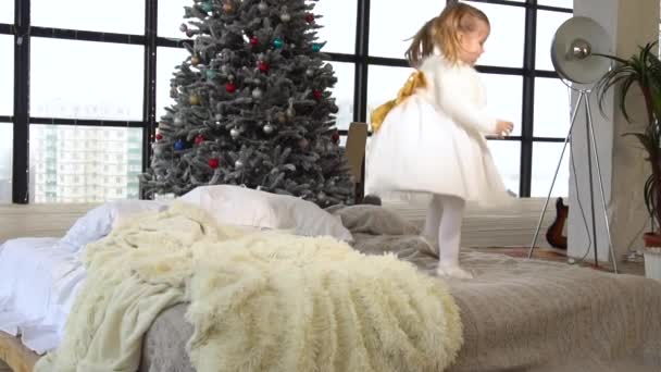Niña feliz saltando en la cama en casa en tiempo de Navidad — Vídeos de Stock
