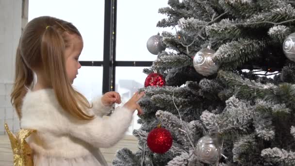 Adorable niña decorar árbol de Navidad con juguetes — Vídeo de stock