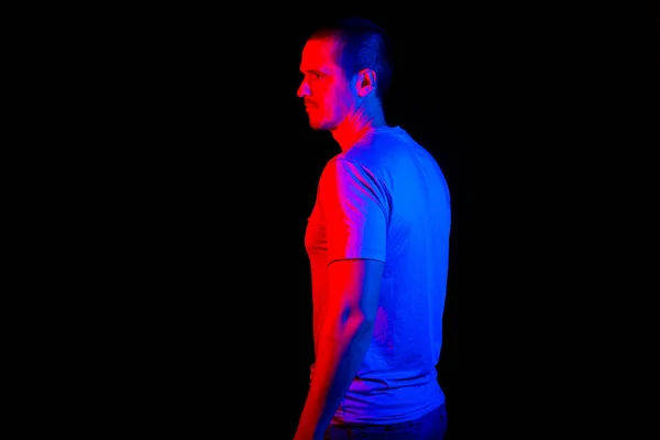 Homme debout en studio sous des lumières de couleur rouge et bleue — Photo