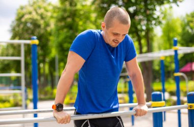 Spor sahasındaki barlarda egzersiz yapan erkek sporcu.