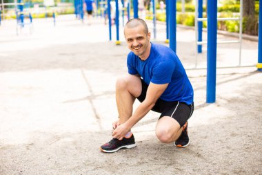 Erkek adam ayakkabı bağı bağlar ve kameraya bakar.
