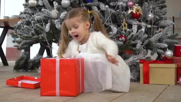 Pequeña chica divertida sorprendida con caja de regalo roja — Vídeo de stock