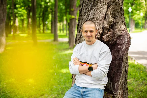 Hombre adulto apoyado en el árbol en el día de verano —  Fotos de Stock