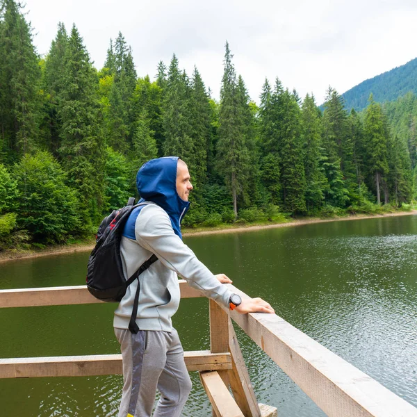 Sırt çantalı bir adam dağ gölüne bakıyor. — Stok fotoğraf