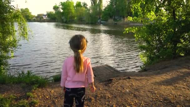 Holčička dívá na řeku v letním večeru — Stock video