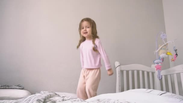Счастливый ребенок прыгает на кровати в замедленной съемке — стоковое видео