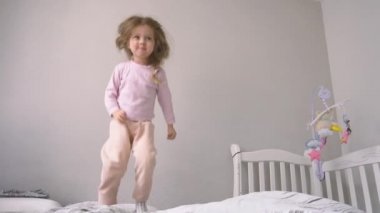 Komik ve mutlu kız yatakta zıplıyor