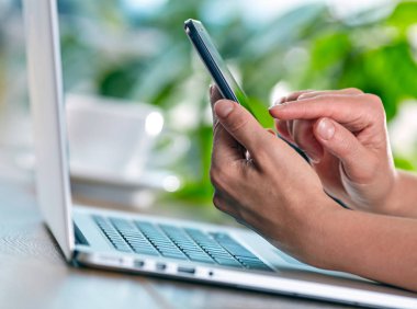 Akıllı telefon ve dizüstü bilgisayar kullanan kadın. 