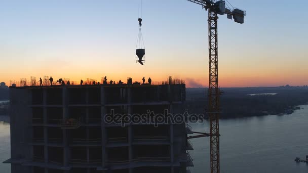 Antenn skott av byggarbetsplatsen med kranar och arbetstagare vid solnedgången — Stockvideo