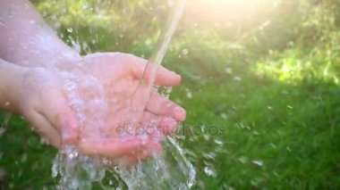 Kadının elinde dökülen su. Yeşil çim doğa arka plan, çevre sorunları. Ağır çekim