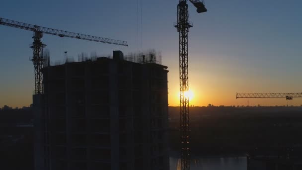 Zdjęcia lotnicze z budowy dźwigów i pracowników o zachodzie słońca — Wideo stockowe