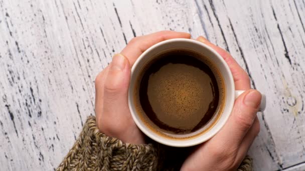 Kvinnliga händer håller kopp kaffe. Skumbrun och orange vätska dricka roterande i vit kopp. Upp och ner, 4k — Stockvideo