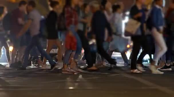 Une foule de personnes traversant la rue à un passage pour piétons le soir. Voitures avec des lumières debout en arrière-plan. UHD — Video