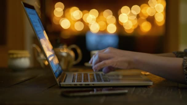 Vrouw die op laptop werkt terwijl ze in een gezellig café of thuis zit met kerstversieringen. Vrouwelijke handen typen op laptop toetsenbord. 4k, Uhd — Stockvideo