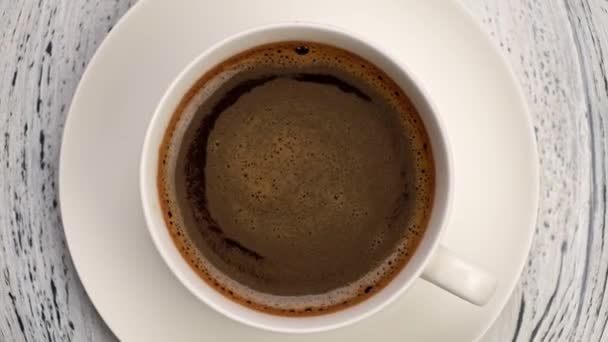 Plan du haut vers le bas de mousse de café tourbillonne dans une tasse blanche avec du café. Vieux fond en bois, zoom arrière plan 