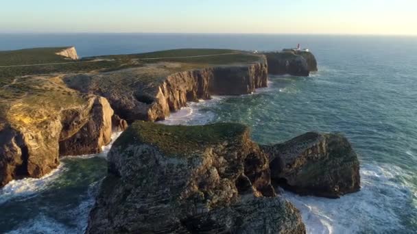 Über flache felsen am cape saint vincent, portugal. Möwen fliegen während des Sonnenuntergangs im tosenden Atlantik umher. Luftaufnahme, uhd — Stockvideo