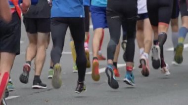 Şehir yolunda koşan maraton koşucuları. Yavaş çekim.