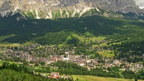 Cortina Dampezzo, Włochy. Miasto w sercu Alp Dolomitowych. Zielona trawa i las pokrywające podnóża. Strzał w przechył, 4k — Wideo stockowe