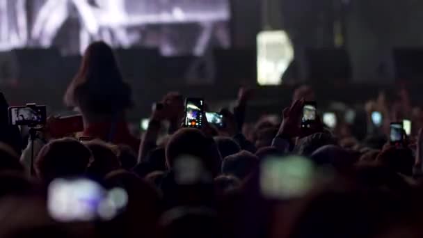 Illuminazione incendi, lampi lampeggianti e fumi che escono durante lo spettacolo sul concerto rock. Gli spettatori guardano lo spettacolo e girano video con i loro smartphone. Luce blu. 4K — Video Stock