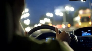 Adam gece şehirde araba sürüyor ve müzik dinliyor. Siyah görünüm