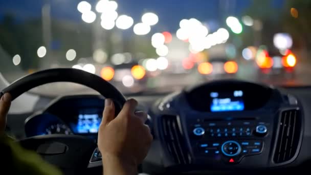 Man hands on steering wheel. Driving car in evening city through traffic jam — Stock Video