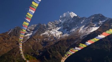 Nepal 'de. Budist yazıtları olan renkli bayraklar güçlü rüzgarda dalgalanıyor. Karlı arka planda Himalaya dağları zirveye ulaştı. Uhd