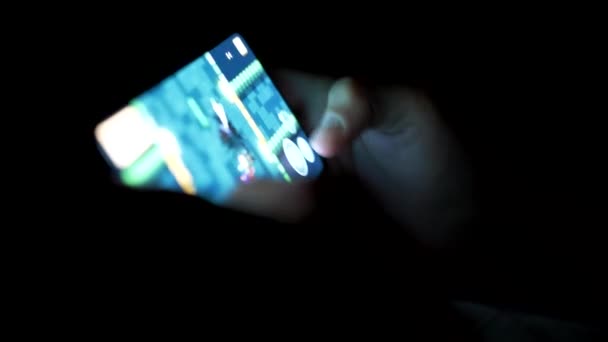 Mobile gaming. Playing game on the smartphone. Hands of young boy in the dark — Stock Video