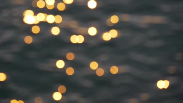 Bokeh of bright blurred orange glare from the sun on the sea water surface. Abstract slow motion shot — 비디오