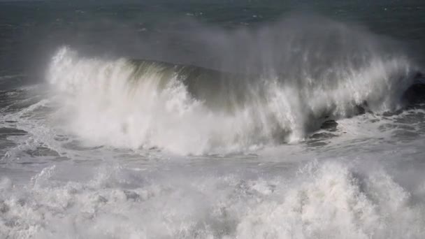 Mocné vlny zuřícího oceánu se pomalu valí a dopadají na pobřeží, způsobují mnoho šplouchnutí bílé pěny. Zpomalený záběr — Stock video