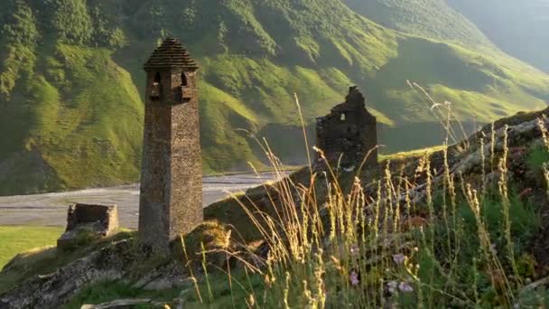 Caucasus Mountains in Tusheti, Georgia. Ruins and the Old Tusheti Tower. Almost dried out stream in the background. Morning sun is lighting green mountains. Crane shot, UHD — 비디오