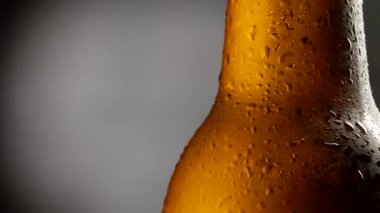 Kahverengi cam bira şişesi arka planda dönüyor. Yakın çekim, 4K