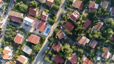 Yeşil bitki örtüsüyle çevrili yüzme havuzları olan tek kişilik aile evleri ve villaların üzerinde uçuyorlar. Yukarıdan aşağıya doğru çekim, Uhd