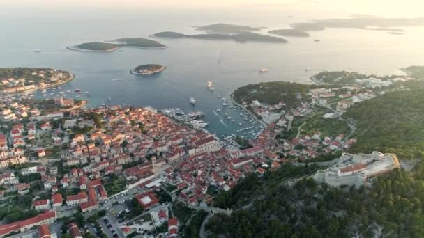 Flug über die Stadt Hvar auf der Insel Hvar, Kroatien. rechts ist die ummauerte spanische Festung zu sehen. Schiffe und Boote fahren am Ufer entlang, viele liegen an der Küste fest. Luftaufnahme, uhd — Stockvideo