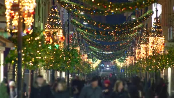 Nepoznatelní lidé chodí po ulici s vánoční a novoroční výzdobou. Jasné vánoční osvětlení ulice. Evropské město zdobené na vánoční prázdniny. Uhd, 4k — Stock video