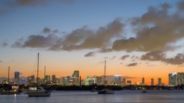 Miami Downtown gökdelenlerinin zaman aşımına uğraması ve gece şehrin ışıklarının yanması. Miami Beach, Florida, ABD 'den görüntü. Uzaklaştır, 4K