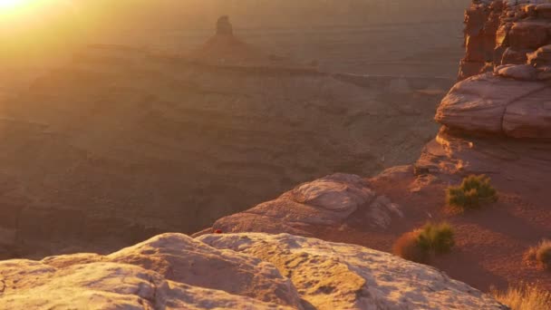 認識できない人々は崖の端に座って日没をお楽しみください。アメリカ、ユタ州のデッド・ホース・ポイント州立公園のジンバル・ショット。UHD, 4K — ストック動画