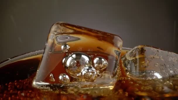 Verre tournant avec boisson pétillante au cola et glaçons. Fond sombre. 4K — Video