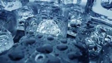Erimiş buz küpleri kapanıyor. Kamera buz küplerinin içinden geçiyor ve arka planda su damlaları var. UHD, 4K