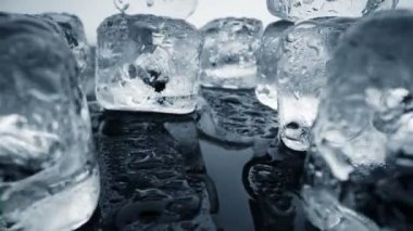 Buz eriyor. Kamera, buz küplerinin ve su birikintilerinin içinden siyah arka planda hareket ediyor. Aşırı ısı ve iklim değişikliği kavramı