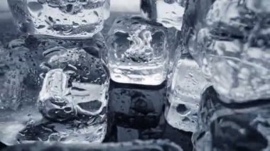 Erimiş buz küpleri kapanıyor. Kamera buz küplerinin içinden geçiyor ve arka planda su damlaları var. UHD, 4K