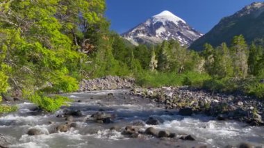 Lanin Ulusal Parkı 'ndaki Lanin volkanı kayıyor. Volkan, dağ nehri ve yeşil ağaçlarla kaplı bir manzara. Arjantin, Patagonya, Göl Bölgesi