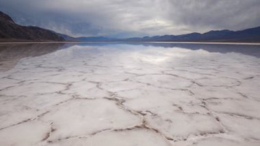 Badwater Havzası, Ölüm Vadisi Ulusal Parkı 'nda tuz tabakası oluşumlarının ayna yüzeyinde yürüyor. Kaliforniya, ABD