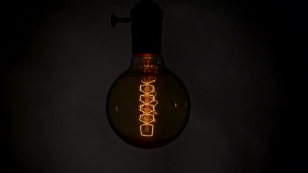 Elektrik kesintisi sırasında Edison lambası yanıp sönüyor ve karanlık bir odada sallanıyor. Yavaş çekim, UHD — Stok video