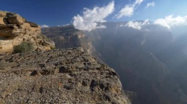 Jebel Shams Dağı, Umman. Bir kayanın kenarında yürüyorum. Kamera ileri gidiyor. Bulutlar ve sis dağı kaplıyor. 4K