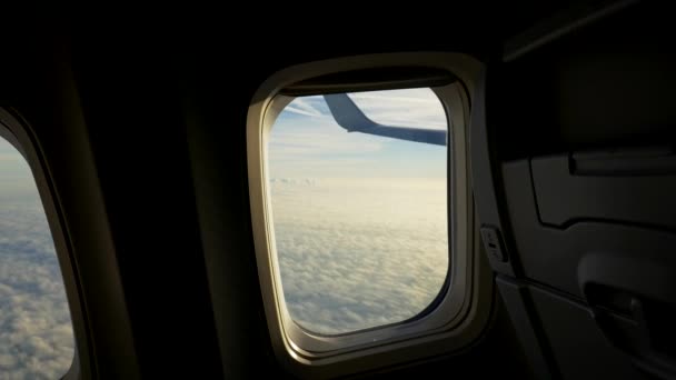 Зйомки відео з аеродрому літаків під час польоту. Камера наближається до вікна і показує, як літак летить над м'якою поверхнею хмари, освітленою сонцем. UHD — стокове відео