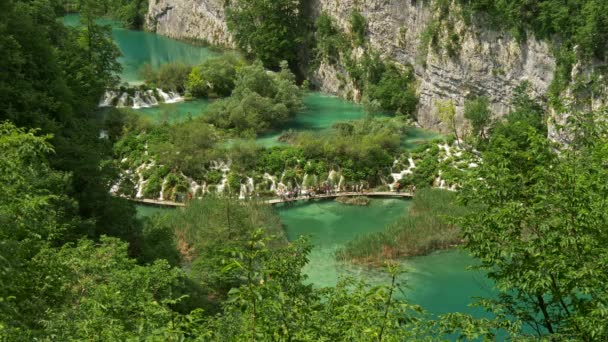 Parque Nacional de los Lagos de Plitvice, Croacia. Vista general de un lago con muchas cascadas pequeñas. Muchos turistas caminando por el paseo marítimo. Verdes ricos, UHD — Vídeo de stock