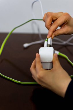 İki kablo ve telefon şarj cihazı tutan kız 
