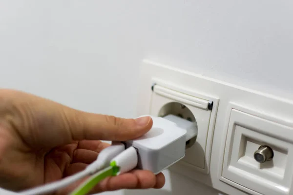 Girl putting phone charger into the socket — Stock Photo, Image