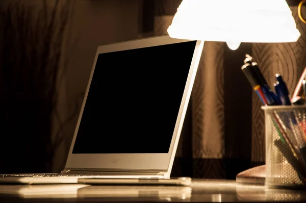 Laptop and lamp on the desk in workplace